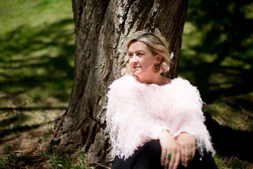 D. LeD sitting against a tree in a pink textured sweater